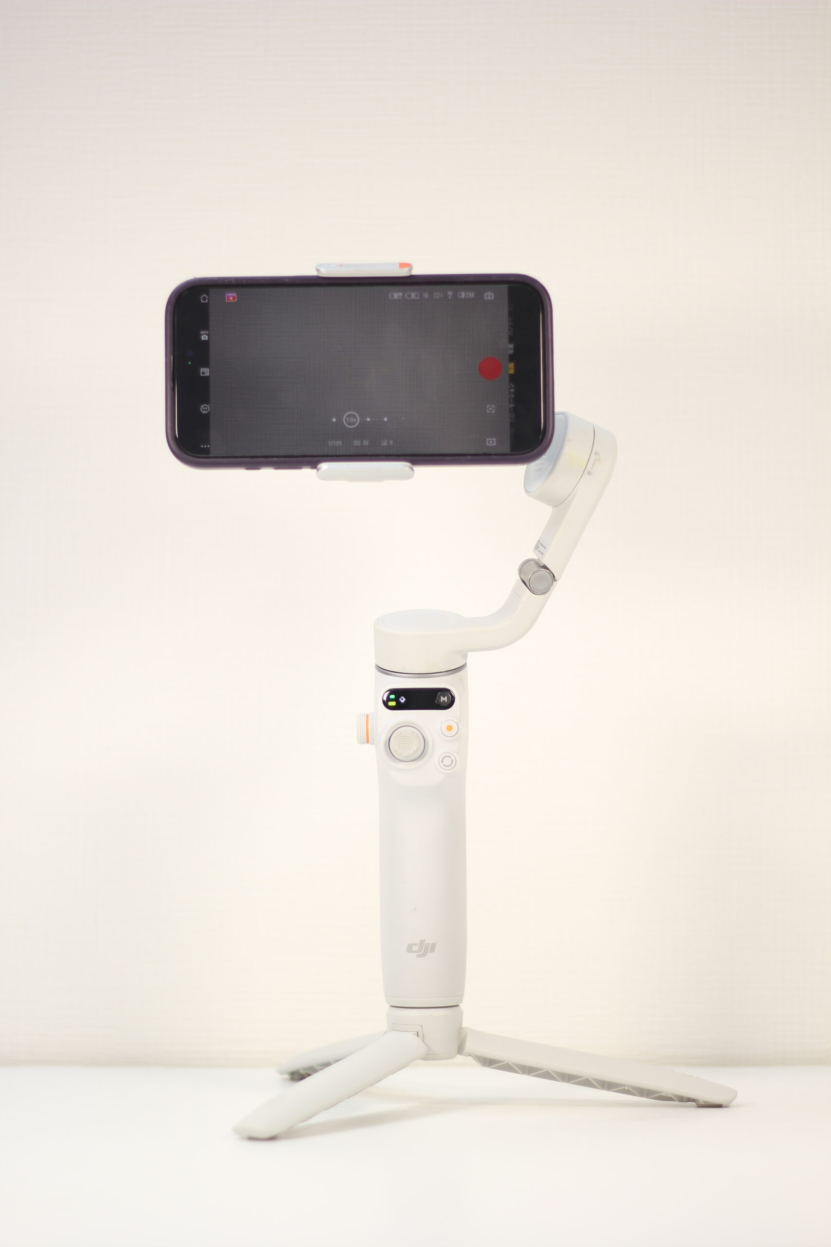 スマートフォンを装着したDJI製の白いジンバルが三脚で自立している。