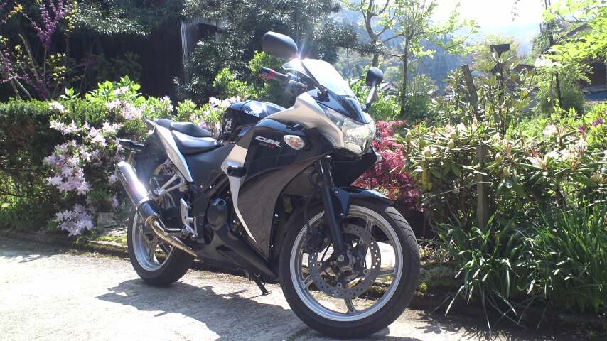 庭先に停められたホンダ CBR250R。黒とシルバーのスポーツバイク。