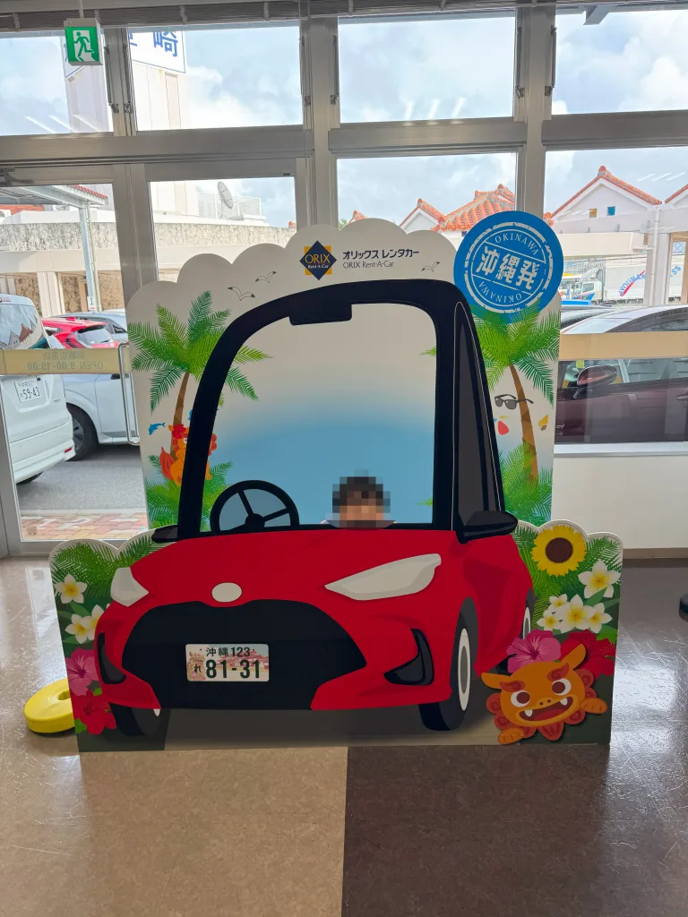 沖縄県内のオリックスレンタカー店舗にある車型の顔出しパネル。子供が運転席に座っているように見えるデザイン。