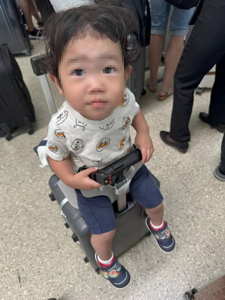 乗れるスーツケースに座って移動中の子ども