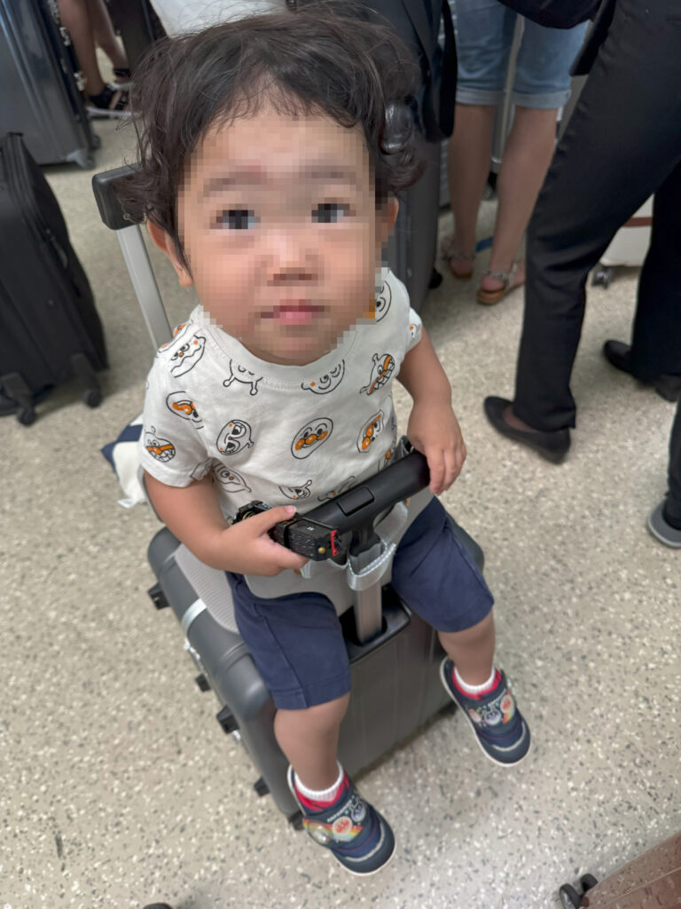 乗れるスーツケースに座って移動中の子ども
