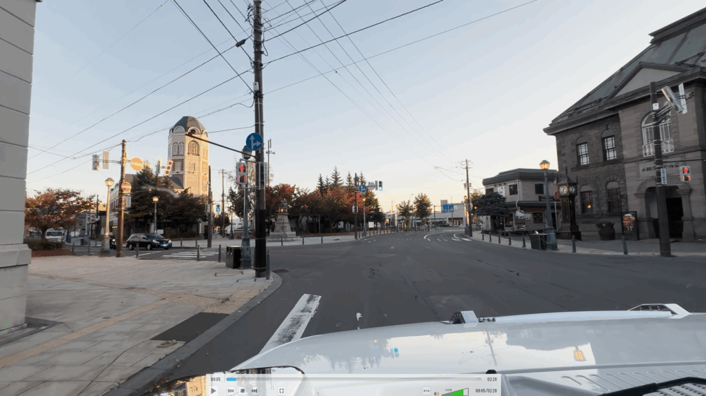 ハマーのフロント越しに眺める早朝の小樽。歴史的な石造りの建物と街灯が異国情緒を漂わせる風景。