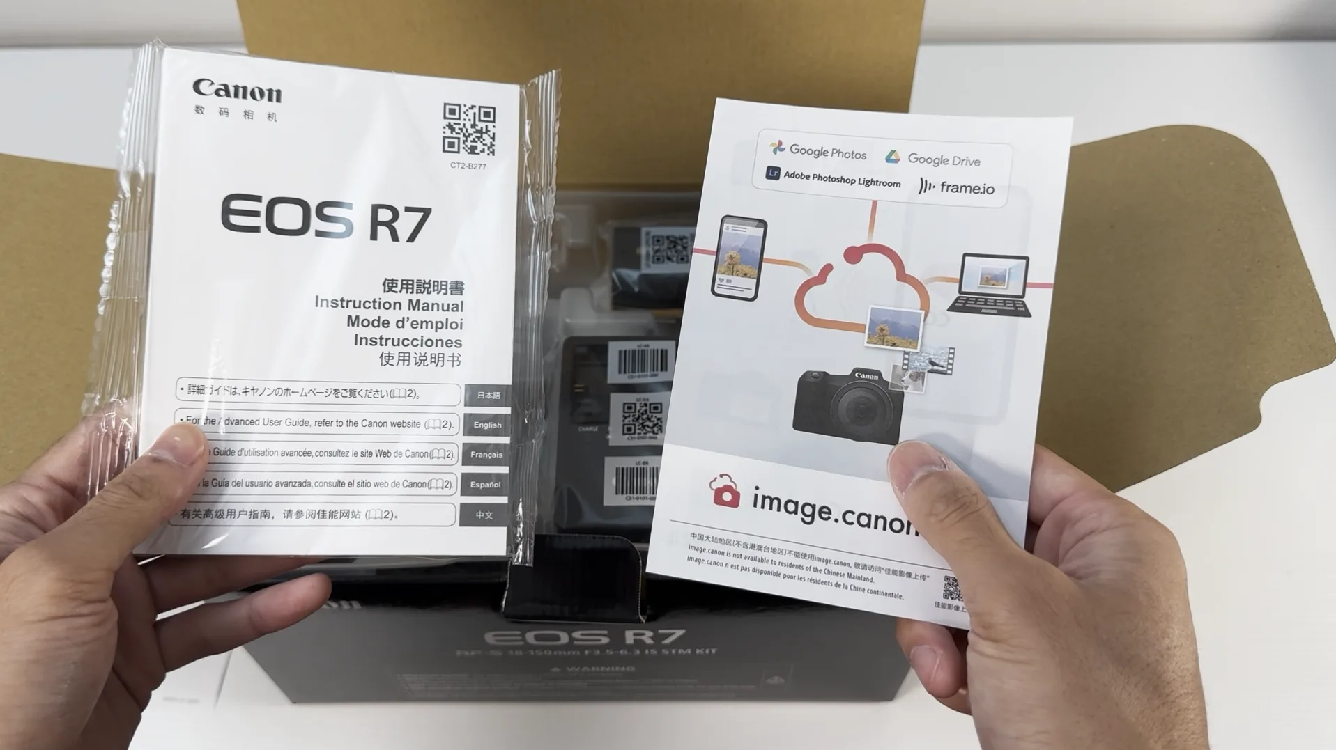 Canon EOS R7の取扱説明書とimage.canonの案内パンフレットを手に持った様子