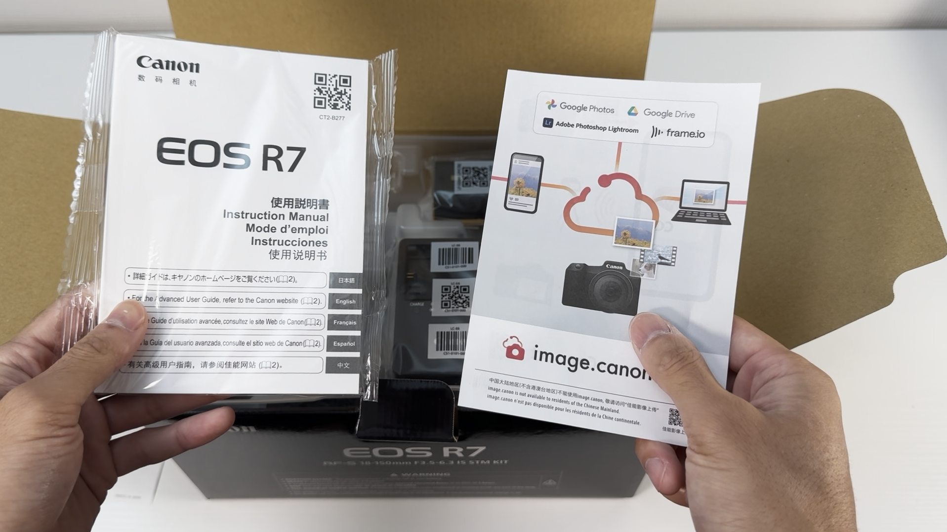 Canon EOS R7の取扱説明書とimage.canonの案内パンフレットを手に持った様子