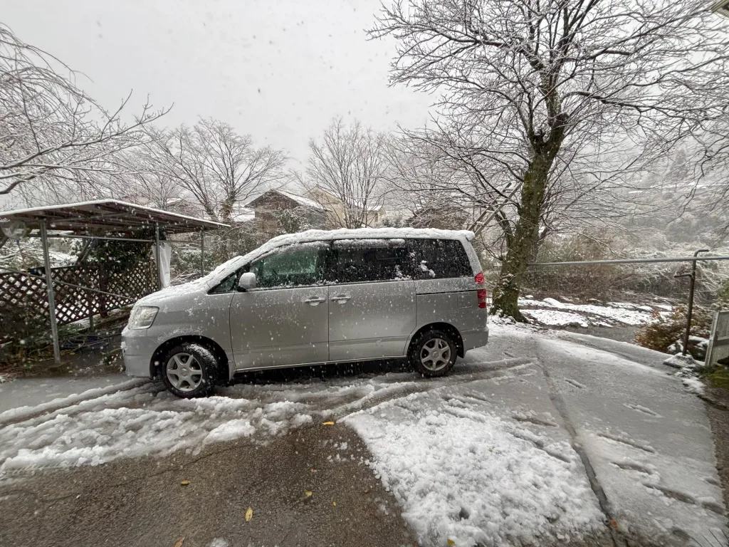 雪が降る中、銀色のミニバンで運転練習中の様子