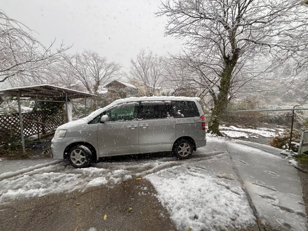 雪が降る中、銀色のミニバンで運転練習中の様子
