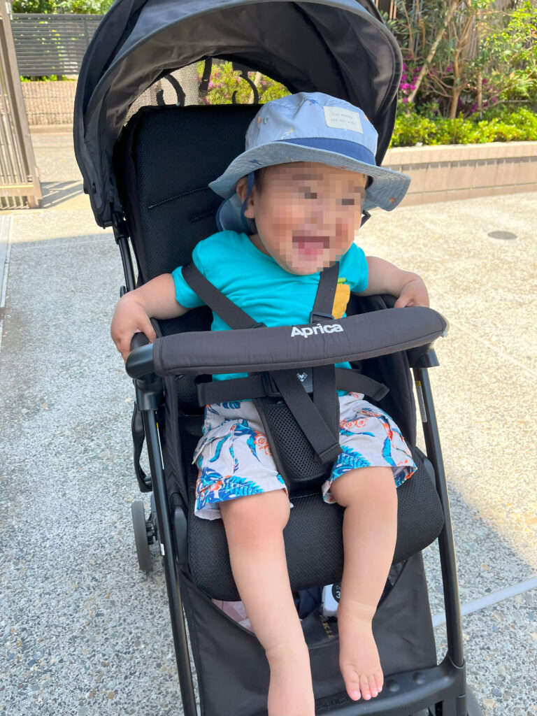 Apricaのベビーカーに乗って笑顔を見せる幼児