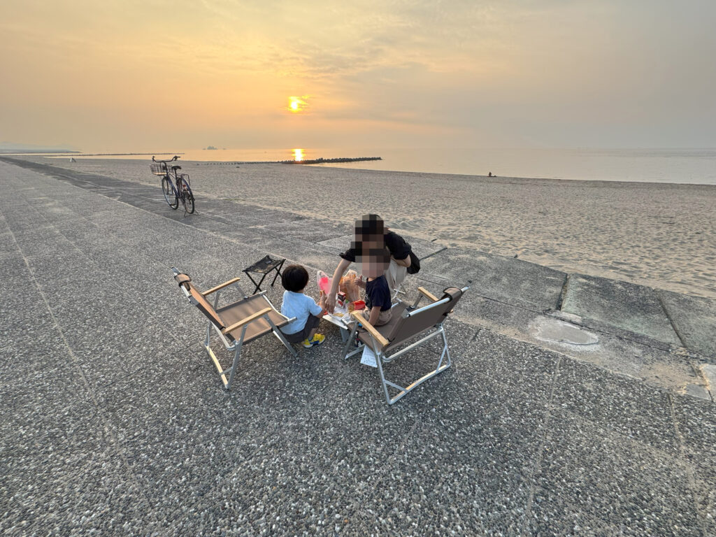 賀露の砂浜で夕日を眺めながら家族でピクニックを楽しむ様子
