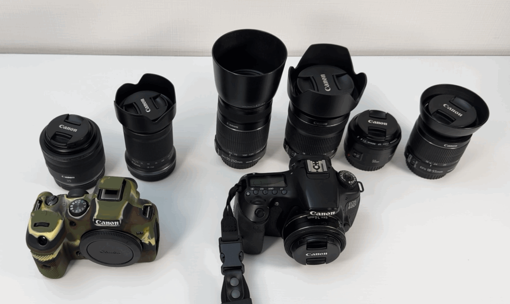 Canon EOS 60Dと複数のCanonレンズを並べた写真。手前には迷彩柄のカメラボディも見える。