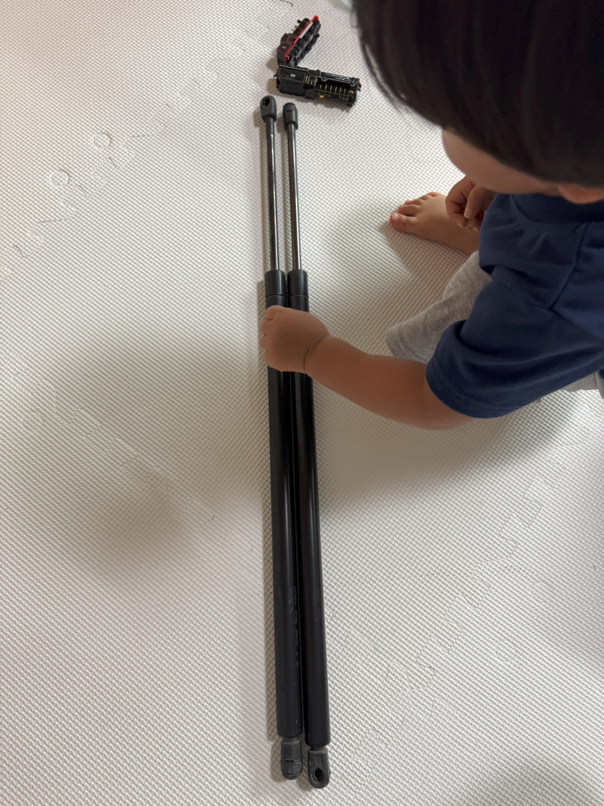 ハマーH2のリアゲートダンパー交換用パーツを手にする子ども