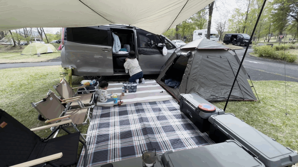 蒜山高原キャンプ場でのオートサイト設営風景。ミニバンとテント、タープを連結したファミリーキャンプの様子