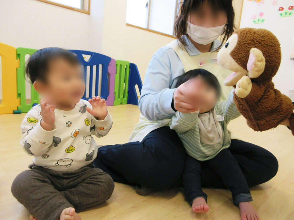 保育園の英語レッスン中 サルのパペットと子どもたちがふれあう様子。