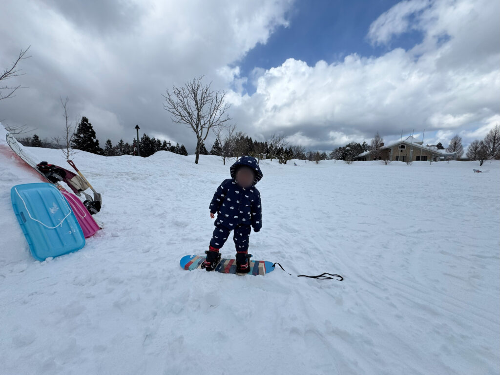 雪の上でスノーボードに立つ子どもの雪遊びの様子
