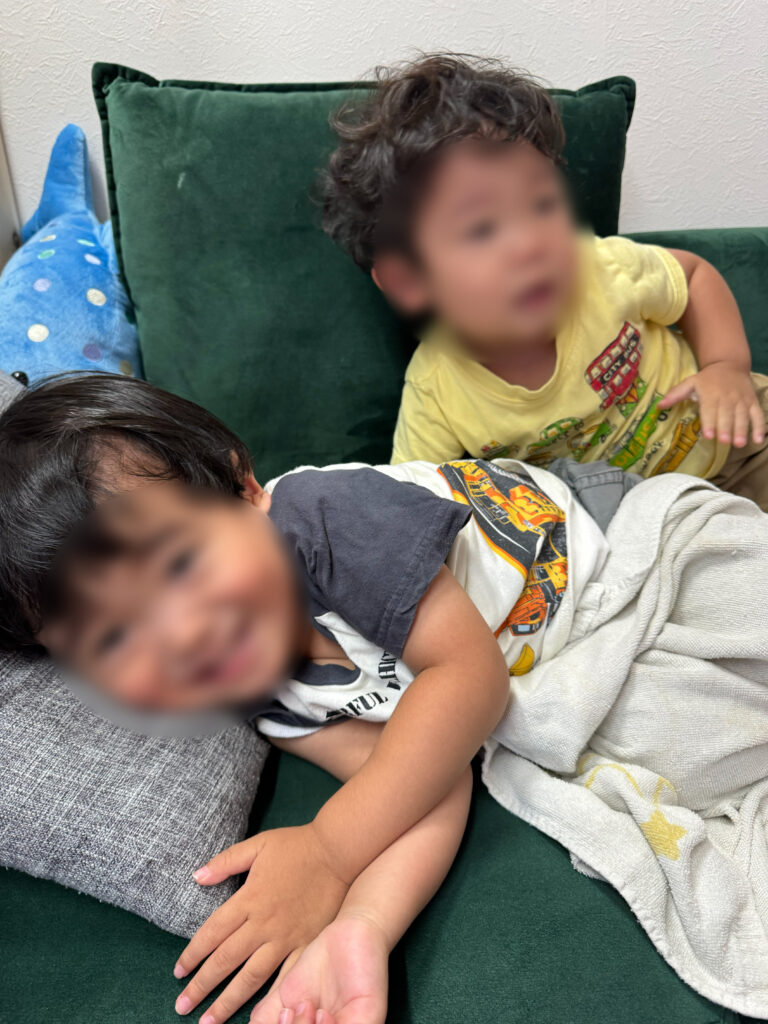 ソファの上で寄り添う年子の兄弟。笑顔でリラックスしながら過ごしている様子。
