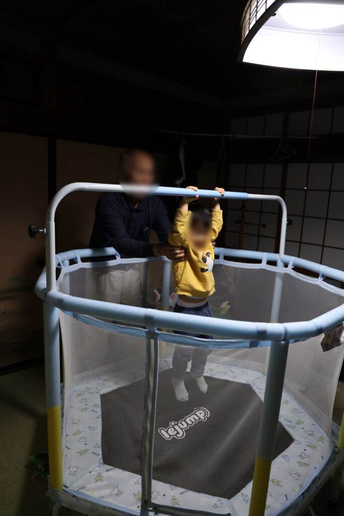 寒い日に室内でトランポリン遊びをする子どもを大人が見守っている様子