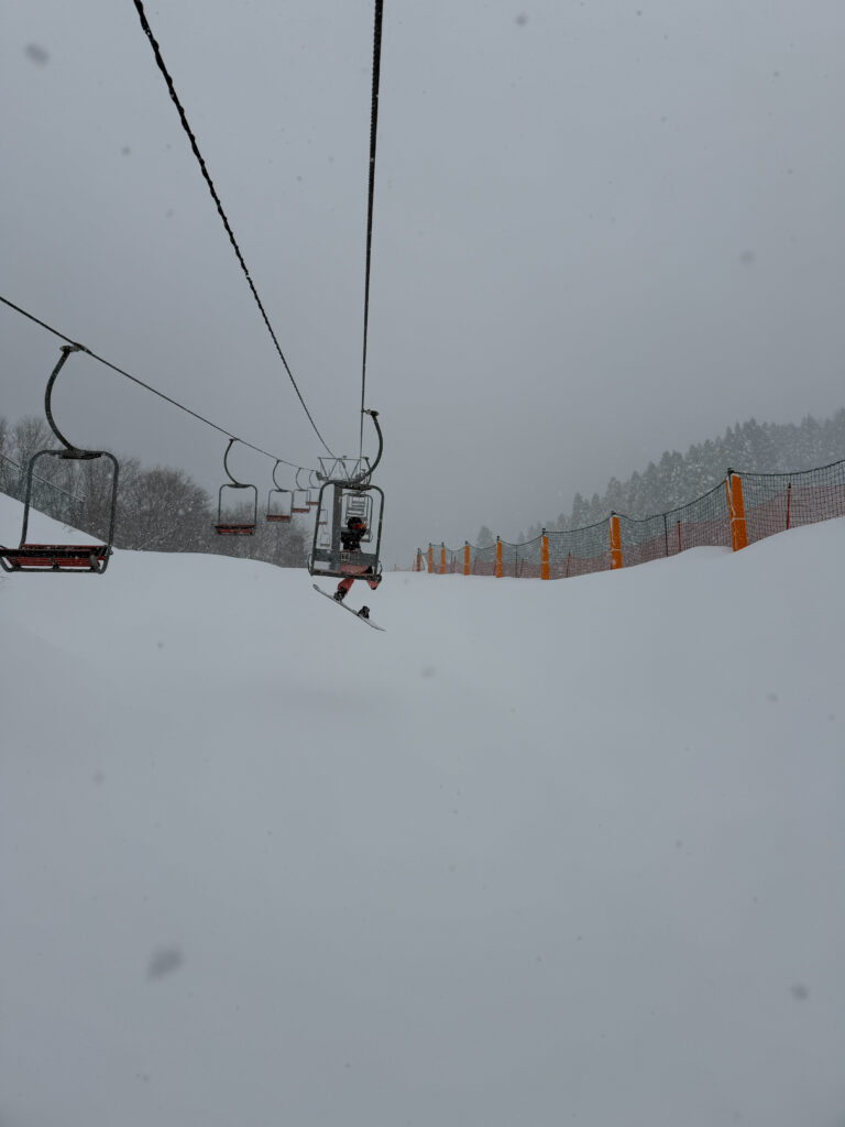 平日のわかさ氷ノ山スキー場で、雪が降る中リフトに乗ってゲレンデ上部へ向かう様子